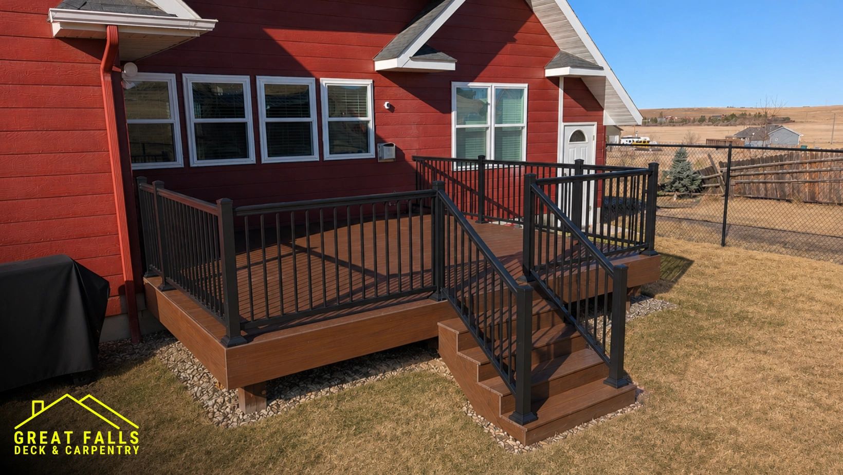 Custom composite deck with black aluminum railing overlooking a spacious Montana backyard.