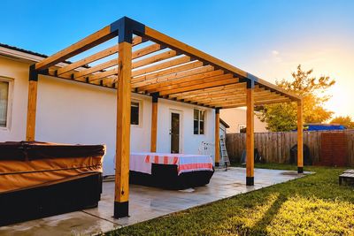 Wooden pergola patio at sunset with lounge seating.