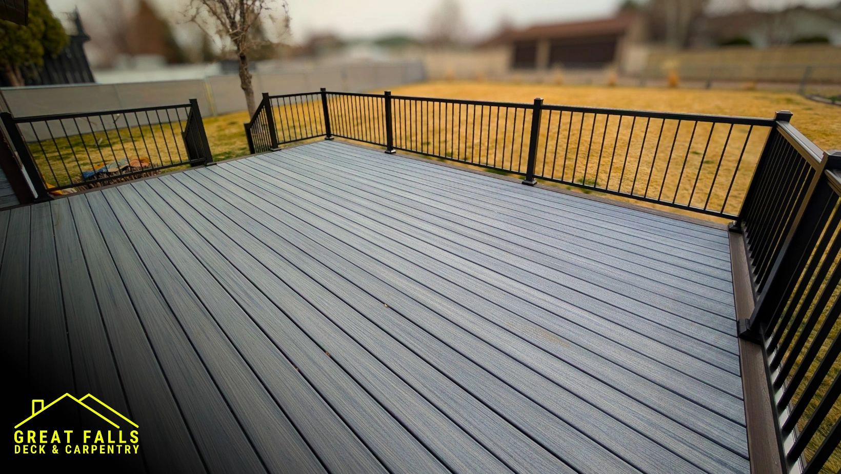 Newly constructed modern outdoor deck with black metal railing and gray wooden flooring.