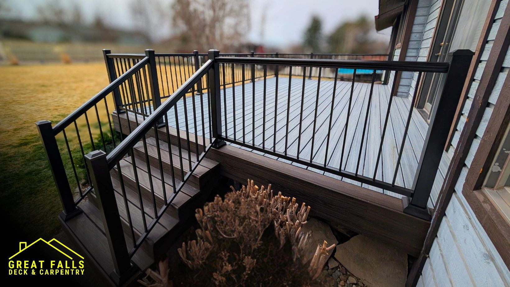 Modern deck with black metal railings and gray wooden flooring.