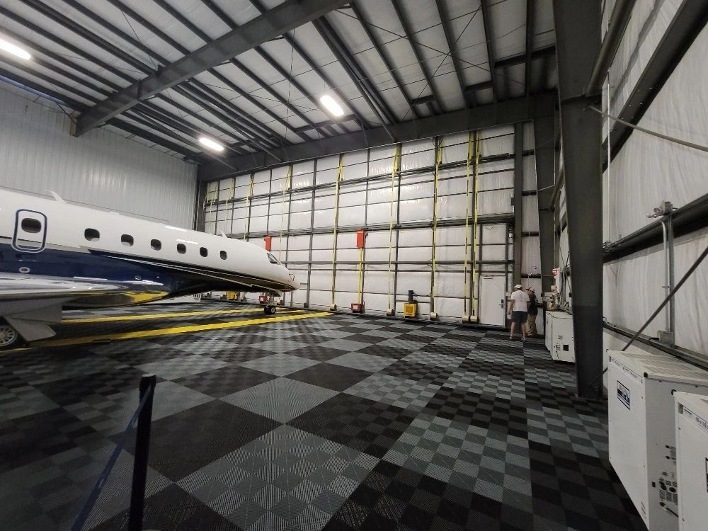 Private jet inside a spacious hangar with checkered flooring.