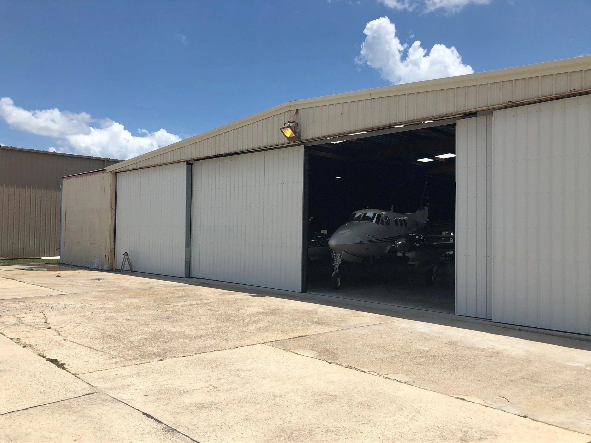 Small plane inside an aircraft hangar on a sunny day.