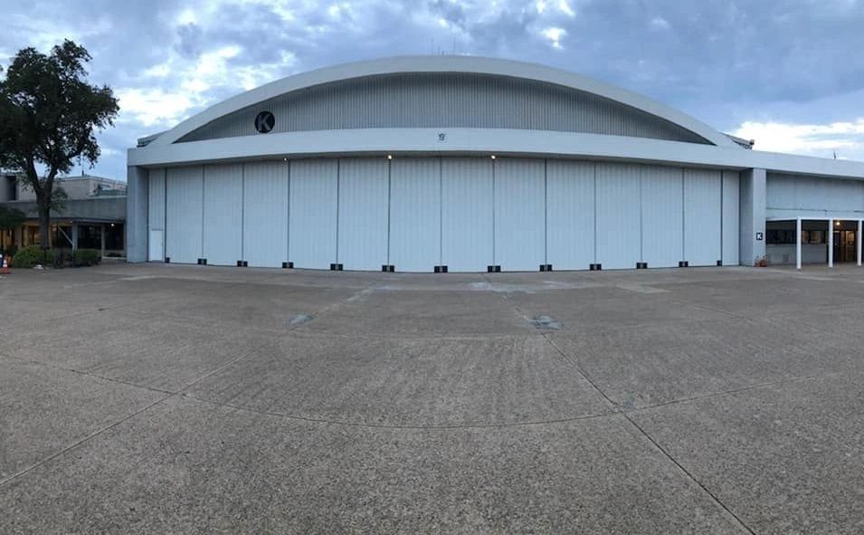 Large white hangar building under cloudy sky.