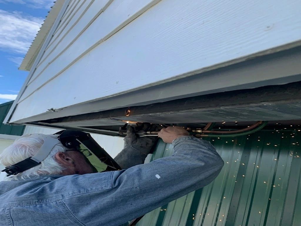 Man welding under a structure wearing protective gear.