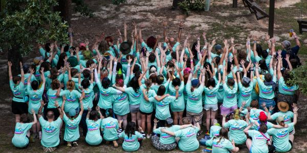 Group of people raising hands in matching shirts.