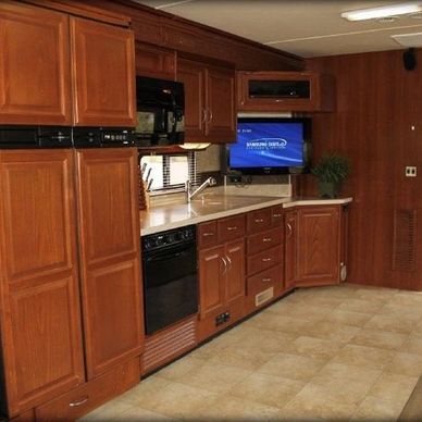 Spacious RV kitchen with wooden cabinets and modern appliances.