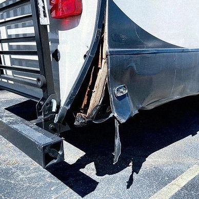 Damaged rear corner of a white vehicle showing exposed internal structure.