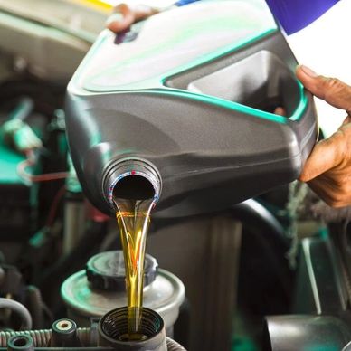 Pouring motor oil into a car engine during maintenance.