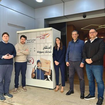 Five people stand beside a Jordan Post smart locker indoors.