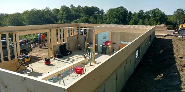 Construction site showing the early framing of a building with workers and tools.