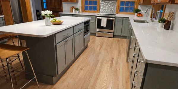 Modern kitchen with wooden floors and white countertops.
