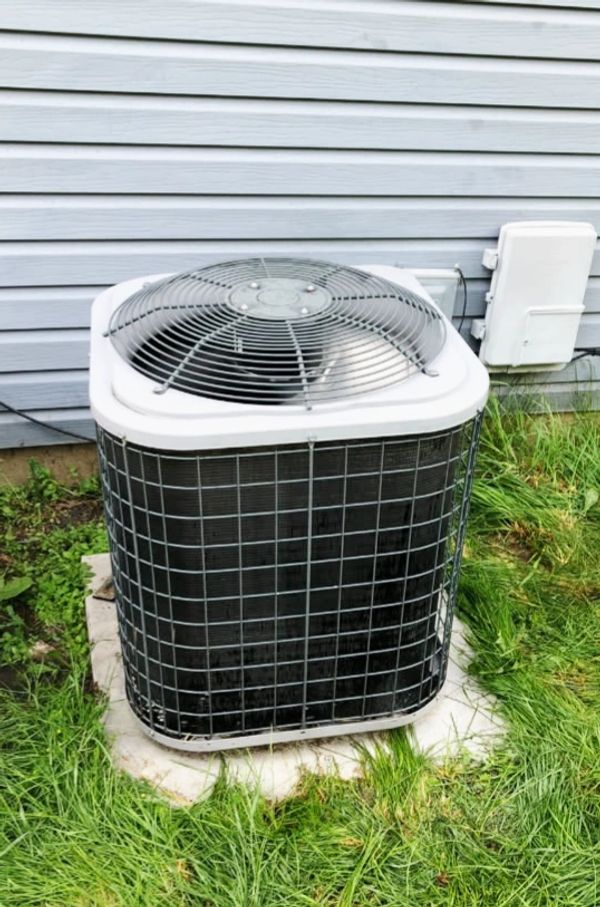 Outdoor air conditioning unit installed beside a house.