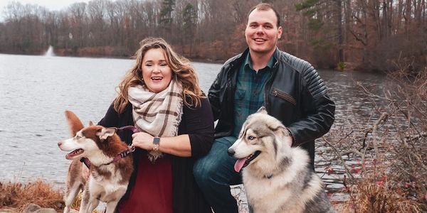 Husband, wife, red and white husky, and gray and white wooly husky by Echo Lake in fall. 