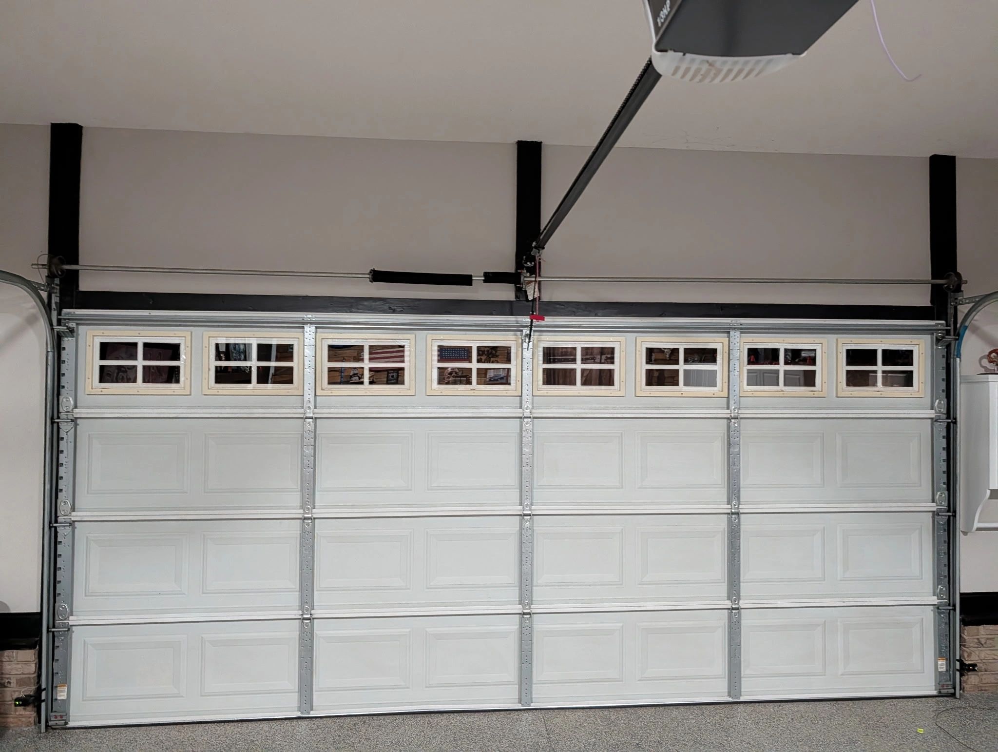 Closed white garage door with small windows on top.