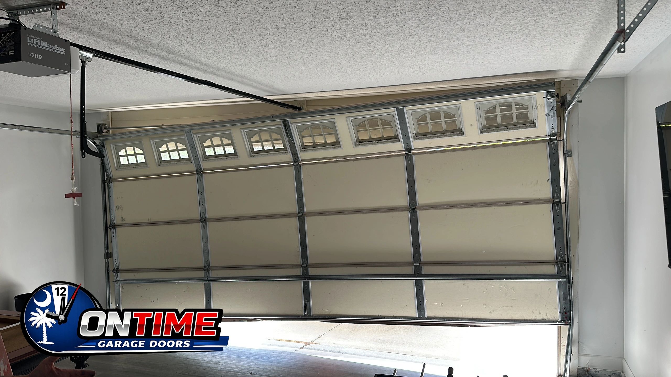 Partially open garage door with On Time Garage Doors logo.