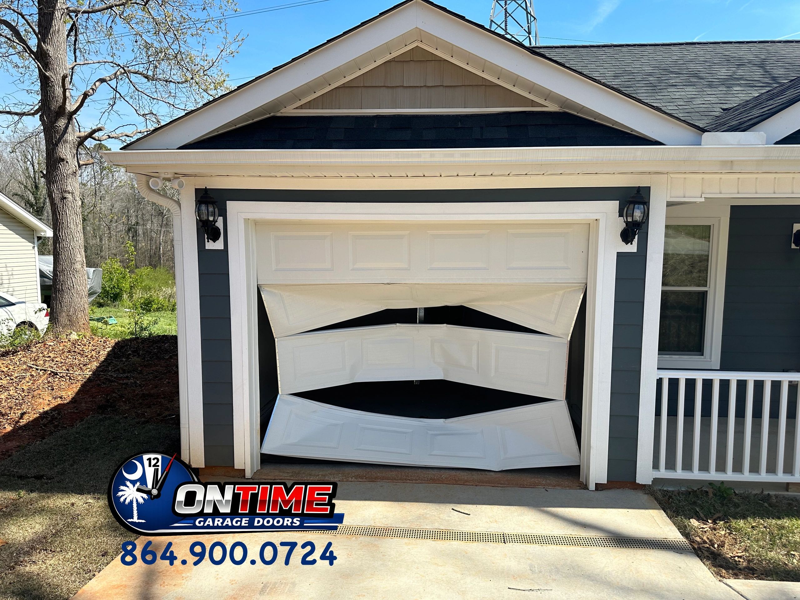 Damaged garage door with contact info for repair service.