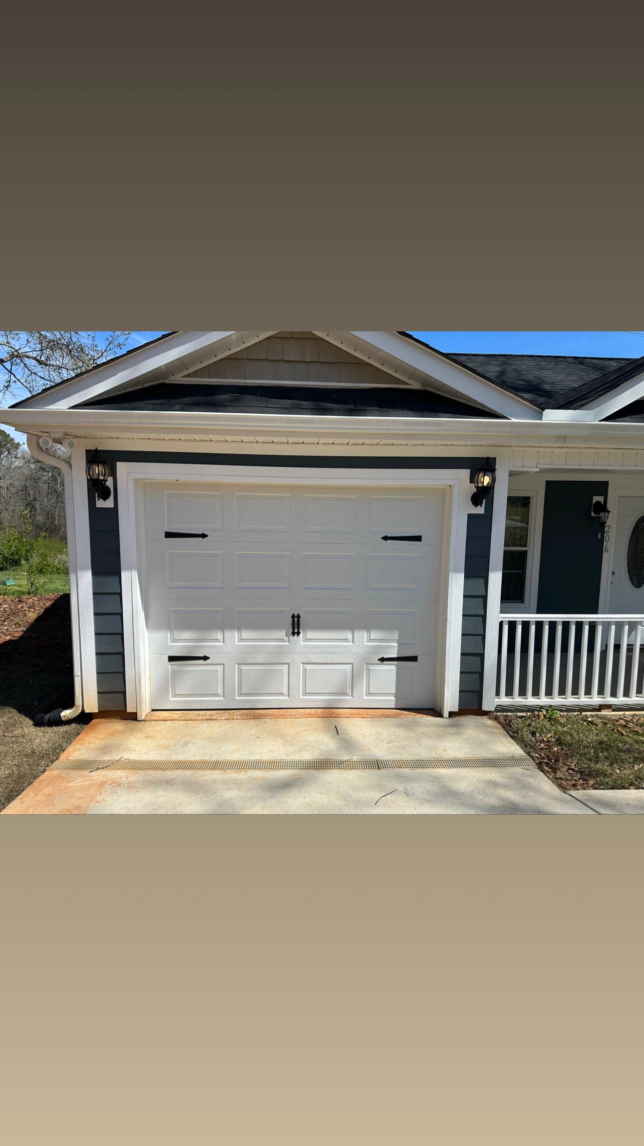 White garage door with black decorative handles on a modern home.