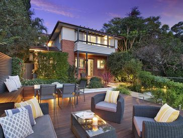 Cozy outdoor seating area with modern furniture in a lush garden at dusk.