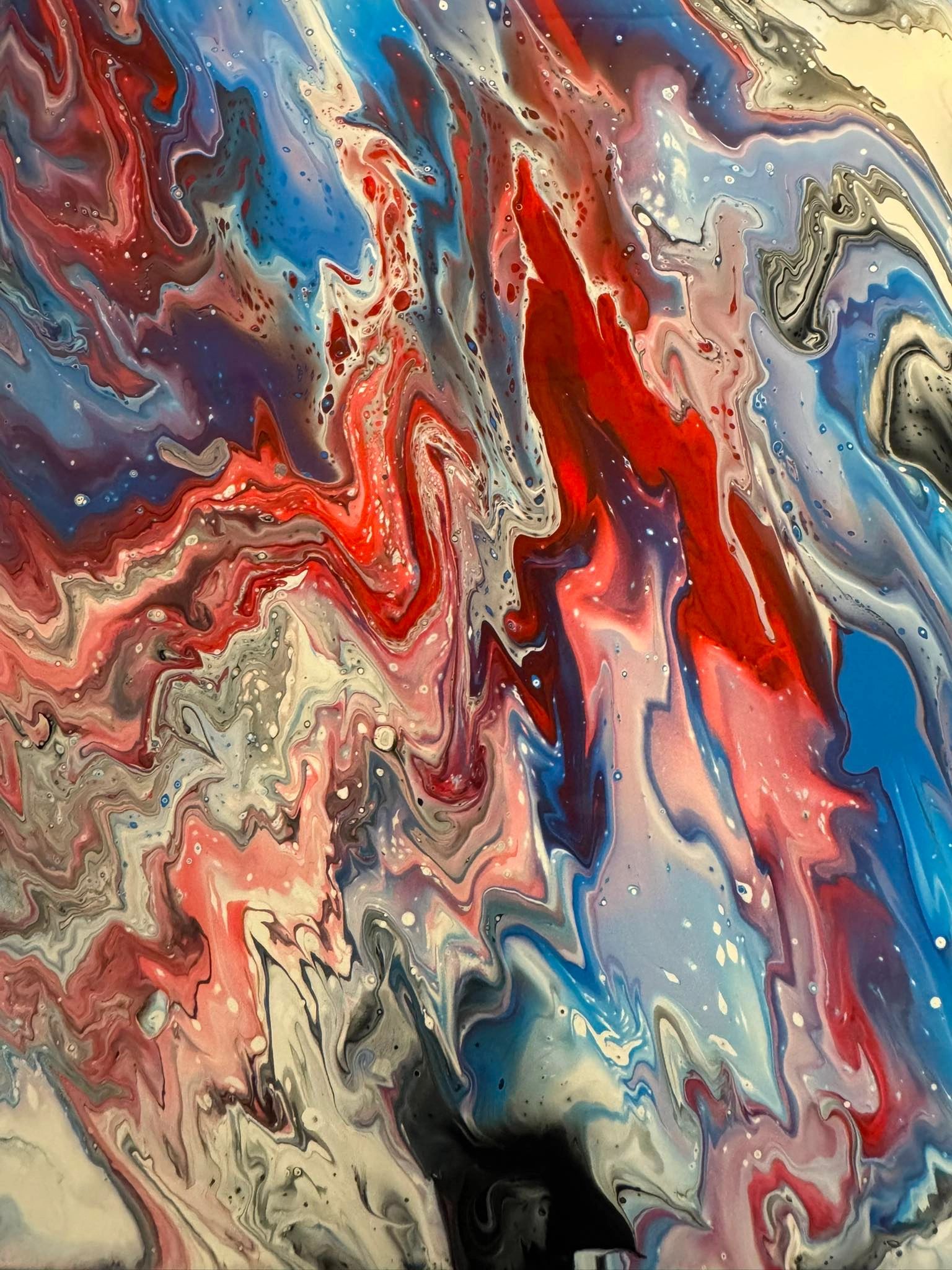 Vivid abstract fluid painting with swirling reds, blues, and creams.