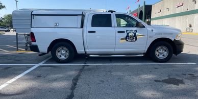 White police pickup truck with logo parked outside a store.
