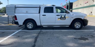 White pickup truck with a logo parked in a lot.