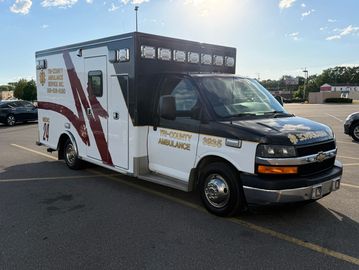 County ambulance parked in a parking lot under clear sky.