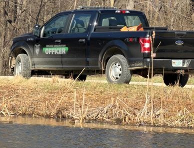 Black officer pickup truck parked near water.