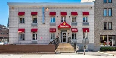 Classic stone building with red window awnings and a central entrance.