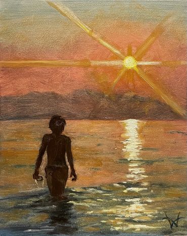A boy wading in a lake at sunset.
