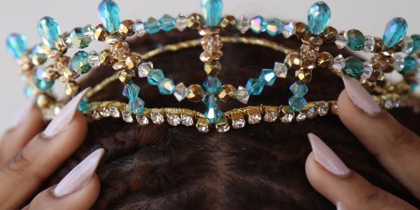 Image of fingers placing a tiara with blue and diamond jewels on someone's head