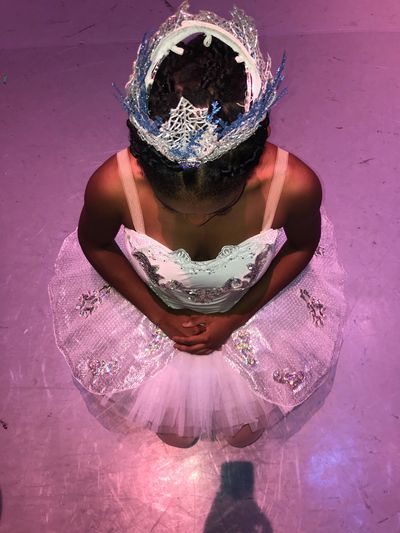 A shot from above of a dancer waiting to go on stage wearing white tutu with jeweled embellishments