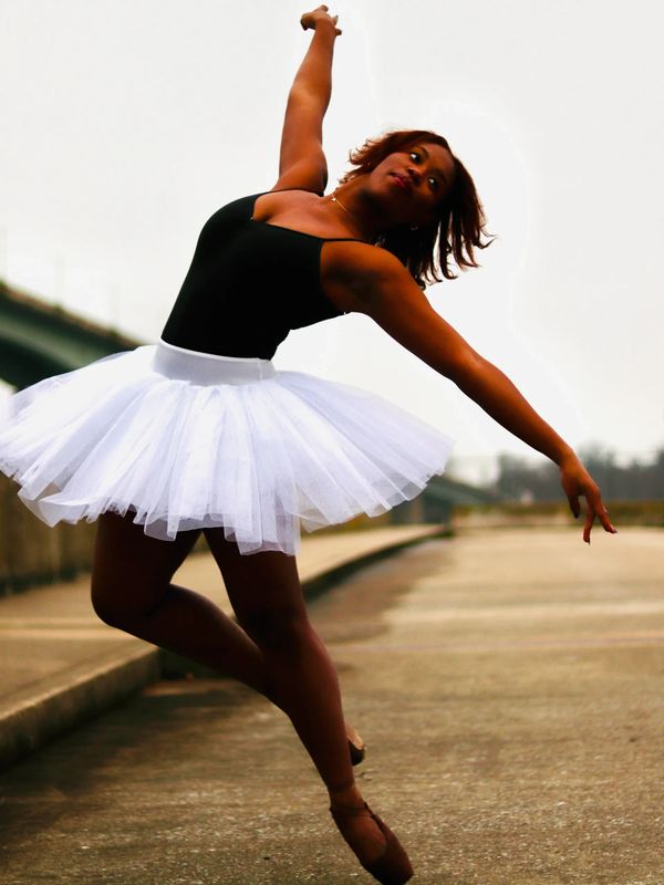 Dancer in white tutu and black leotard falling out of an action pose