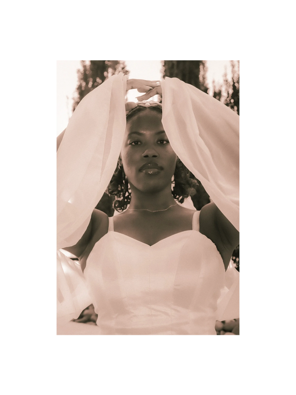 Dancer in white bodice and chiffon sleeves with hands above her head