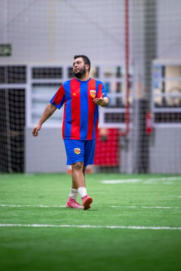 Jogador de futebol indoor com uniforme azul e vermelho.
