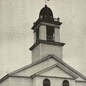 Black and white image of a historic church with a tall steeple and arched windows.