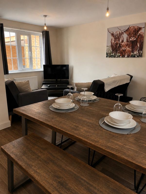 Cozy dining and living area with wooden table and animal painting.