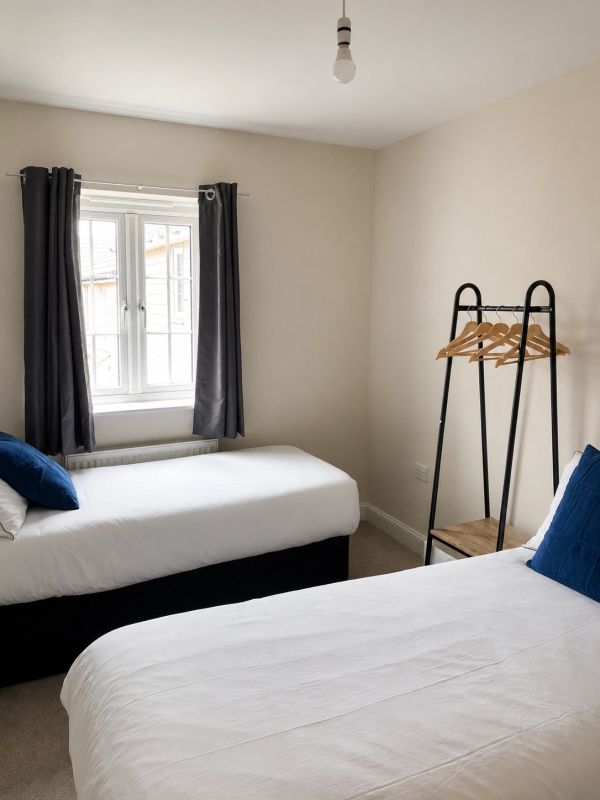 Minimalist twin bedroom with white bedding and blue pillows.