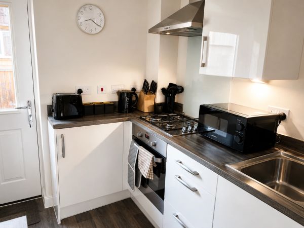 Modern white kitchen with appliances and wooden floor.