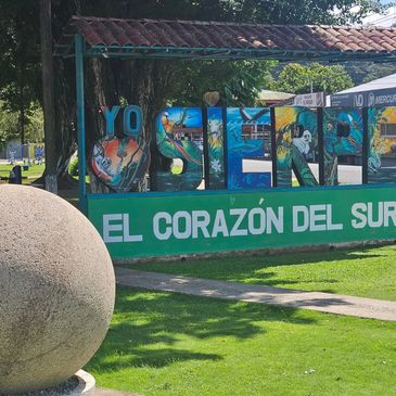 Colorful sign saying "Yo $ienf" and "El Corazón Del Sur" in a park.