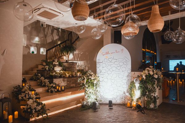 Elegant indoor wedding decor with flowers, candles, and hanging lanterns.