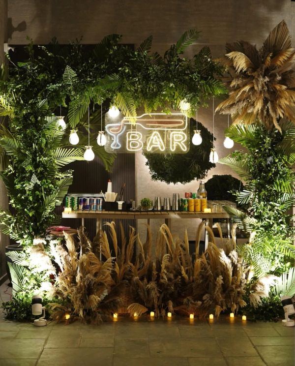 A cozy bar setup with lush greenery and warm lighting.