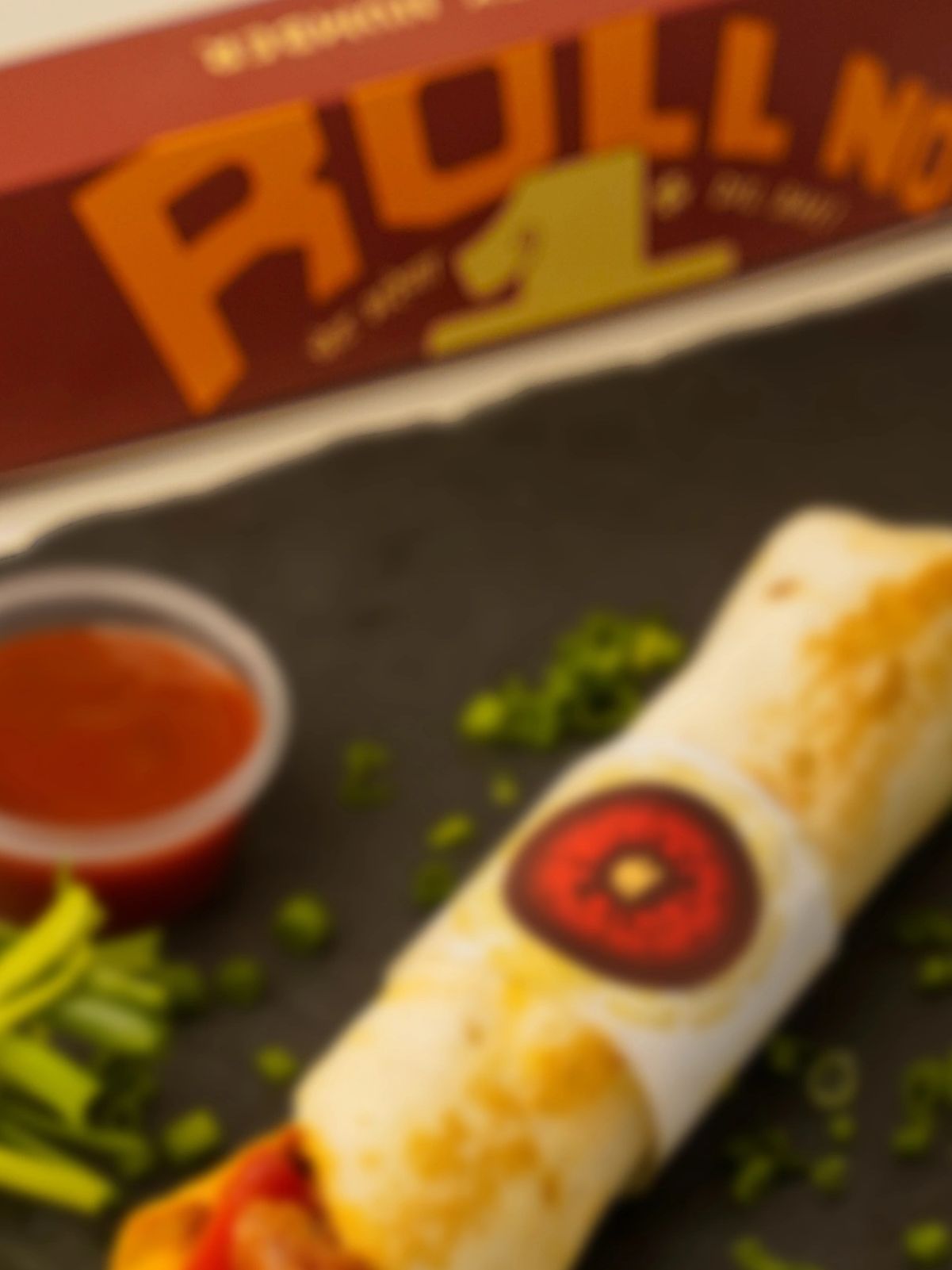 A wrapped burrito with a side of salsa and garnished with chopped green herbs.