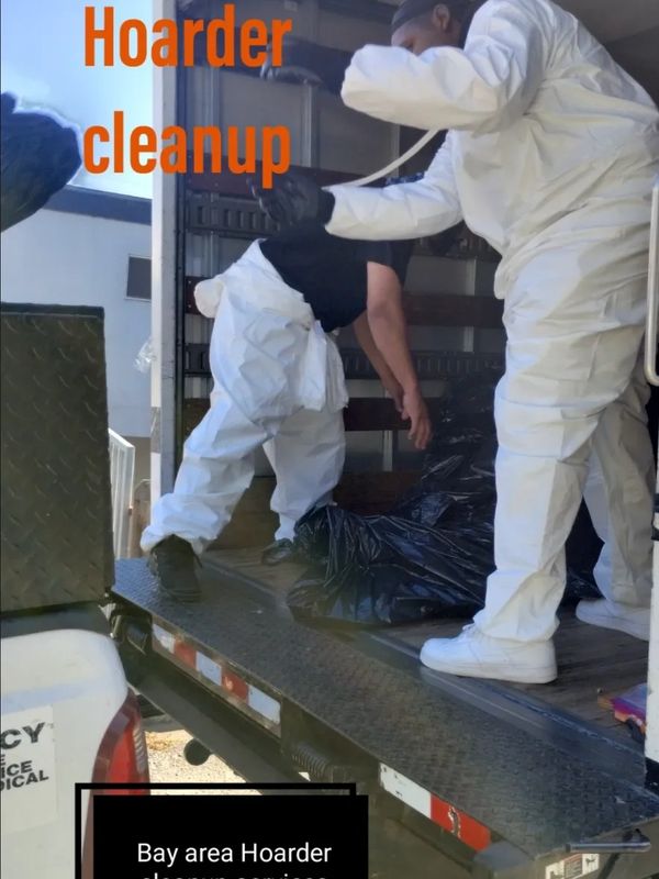  a person in a hazmat suit and gloves standing in a cluttered room, with boxes and other items 94550