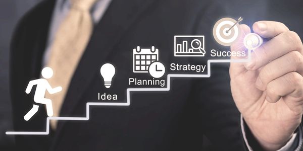 Businessman drawing steps from idea to success with icons for planning and strategy.