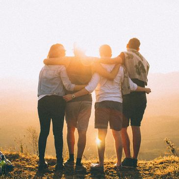 A group of friends hugging in a line in the sunshine