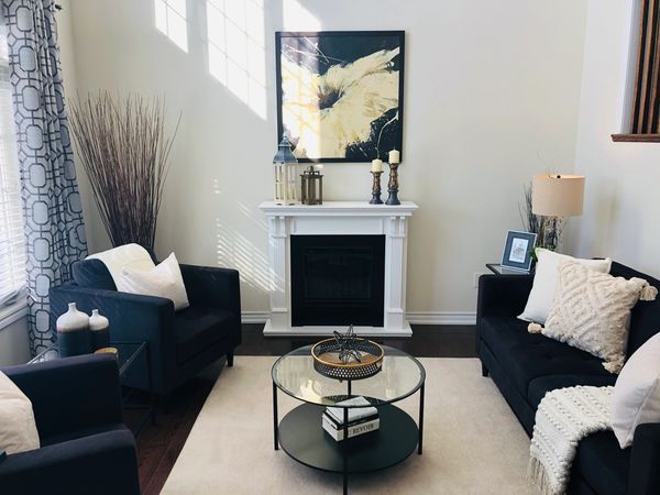 Cozy living room with dark furniture and light-coloured accessories focussed around a fireplace.