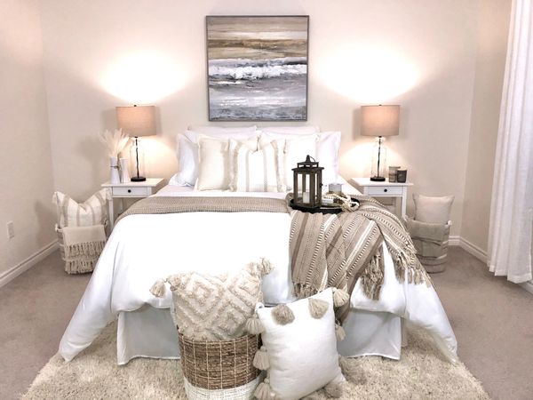 Bohemian inspired bedroom in a neutral palette with loads of pillows, blankets, and accessories