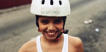 Clever as a Kid Smiling with an old helmet on.
