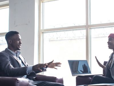 Two professionals engaged in a discussion in a modern office setting.