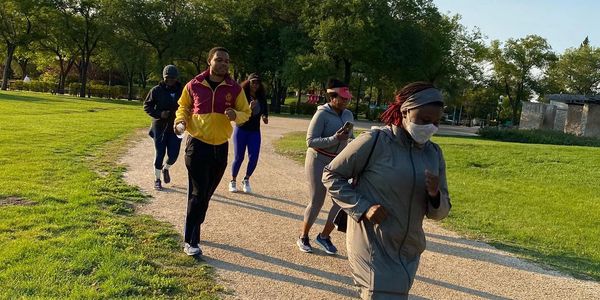 A group of people jogging on a park trail in the morning.